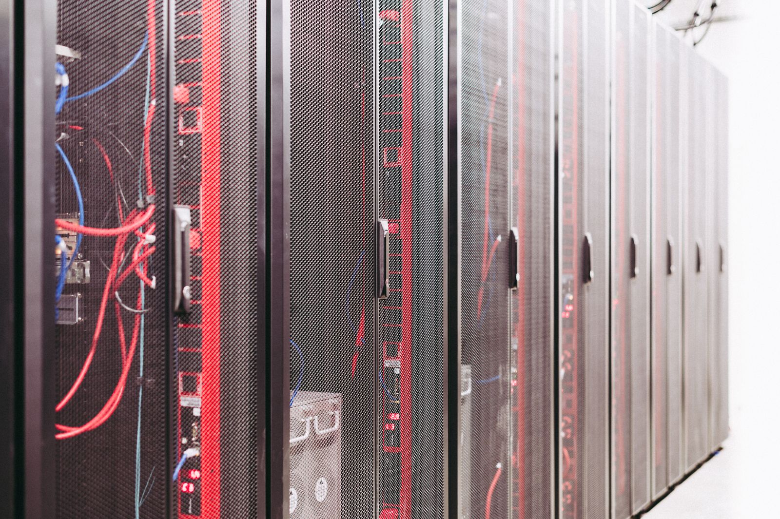 A row of server cabinets with red and blue cables in a data center