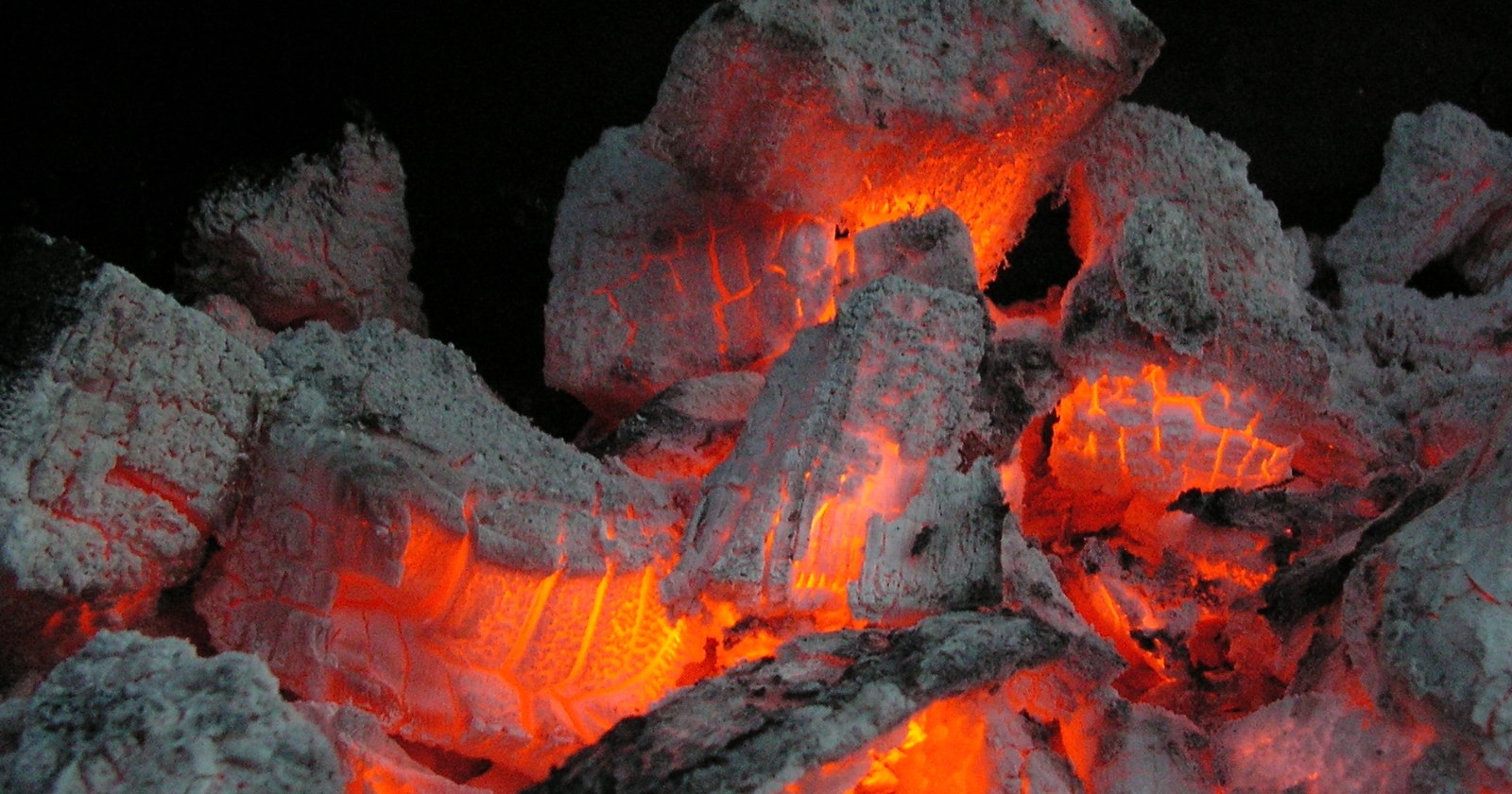 Glowing orange embers showing through a crust of grey ash