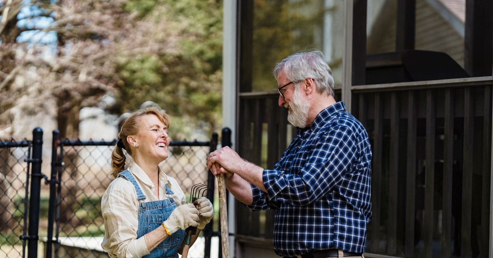 An older couple laughing together while gardening in their backyard